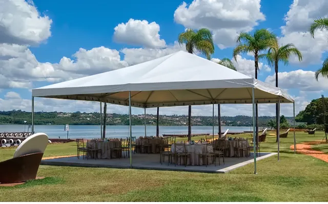 Tenda branca montada em área gramada perto de piscina